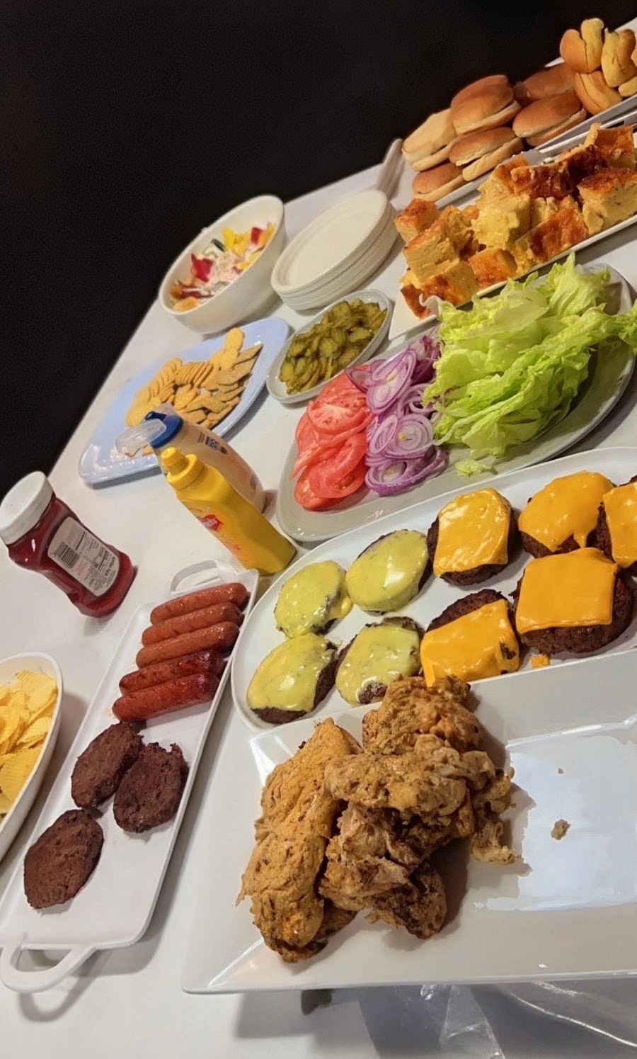 Full catering buffet with burgers, hot dogs, fried chicken, cornbread, and fresh toppings