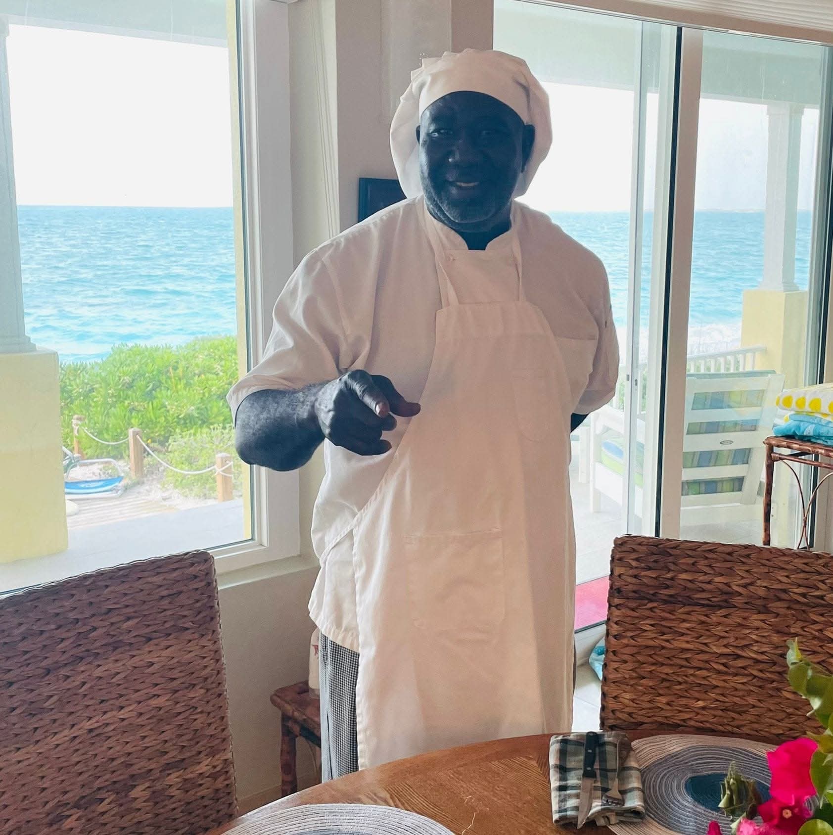 Chef Julian “Cheater” Romer in his chef whites with the Bahamian ocean behind him